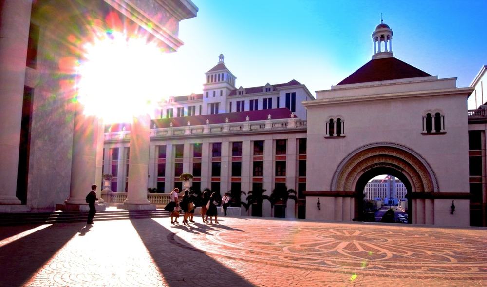 Students crossing the plaza beneath the campus arch in morning sun