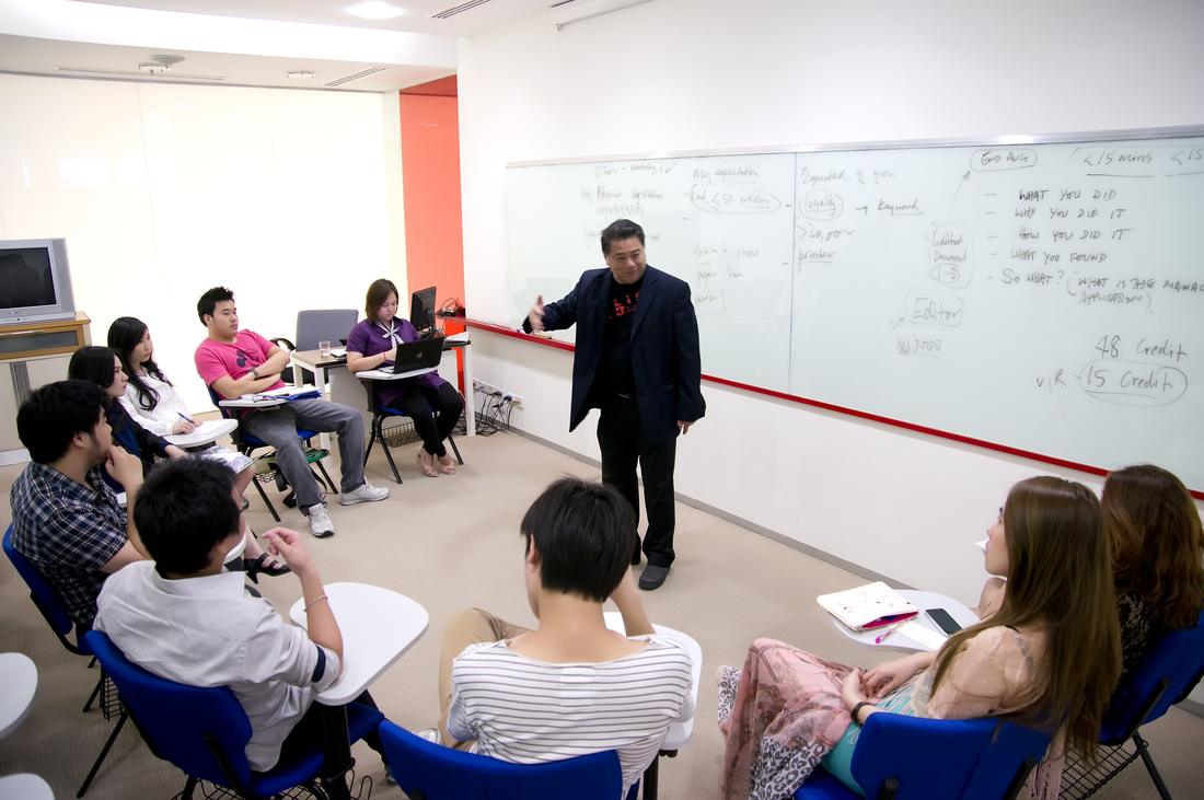 A graduate seminar in progress with a lecturer at the whiteboard